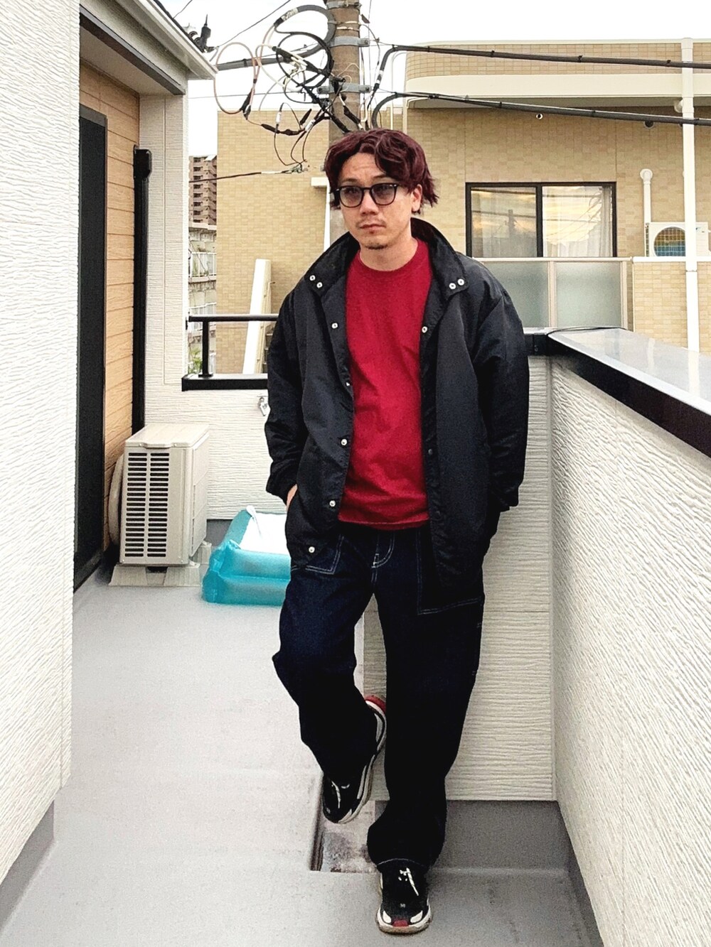 レッド系のTシャツ/カットソー、ブルー系のデニムパンツ、ブラック系のシューズを着用したメンズの秋コーディネートの3枚目の写真