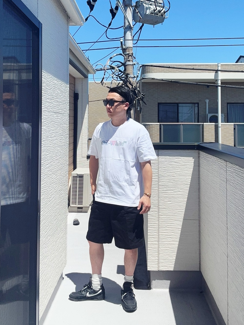 ホワイト系のTシャツ/カットソー、ブラック系のパンツ、ブラック系のスニーカーを着用したメンズの夏コーディネートの2枚目の写真