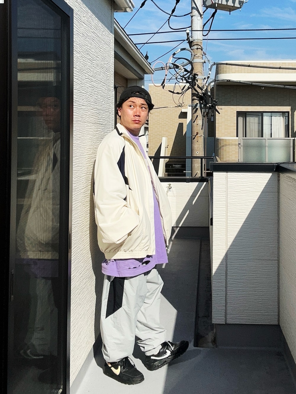 グレー系のその他パンツ、パープル系のTシャツ/カットソー、ホワイト系のナイロンジャケットを着用したメンズの秋コーディネートの2枚目の写真