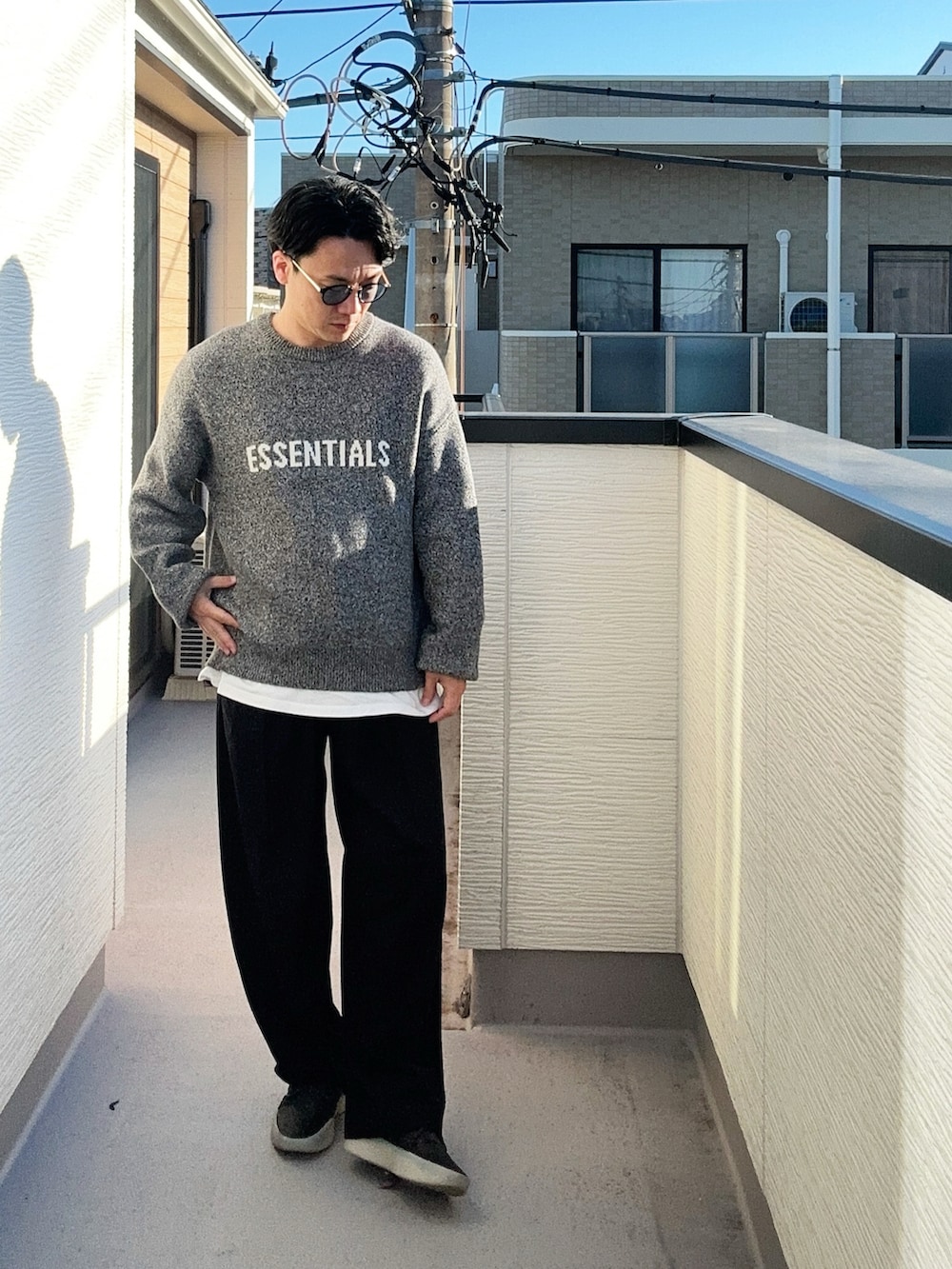 グレー系のニット/セーター、ブラック系のその他アウター、ブラック系のスラックスを着用したメンズの冬コーディネートの2枚目の写真