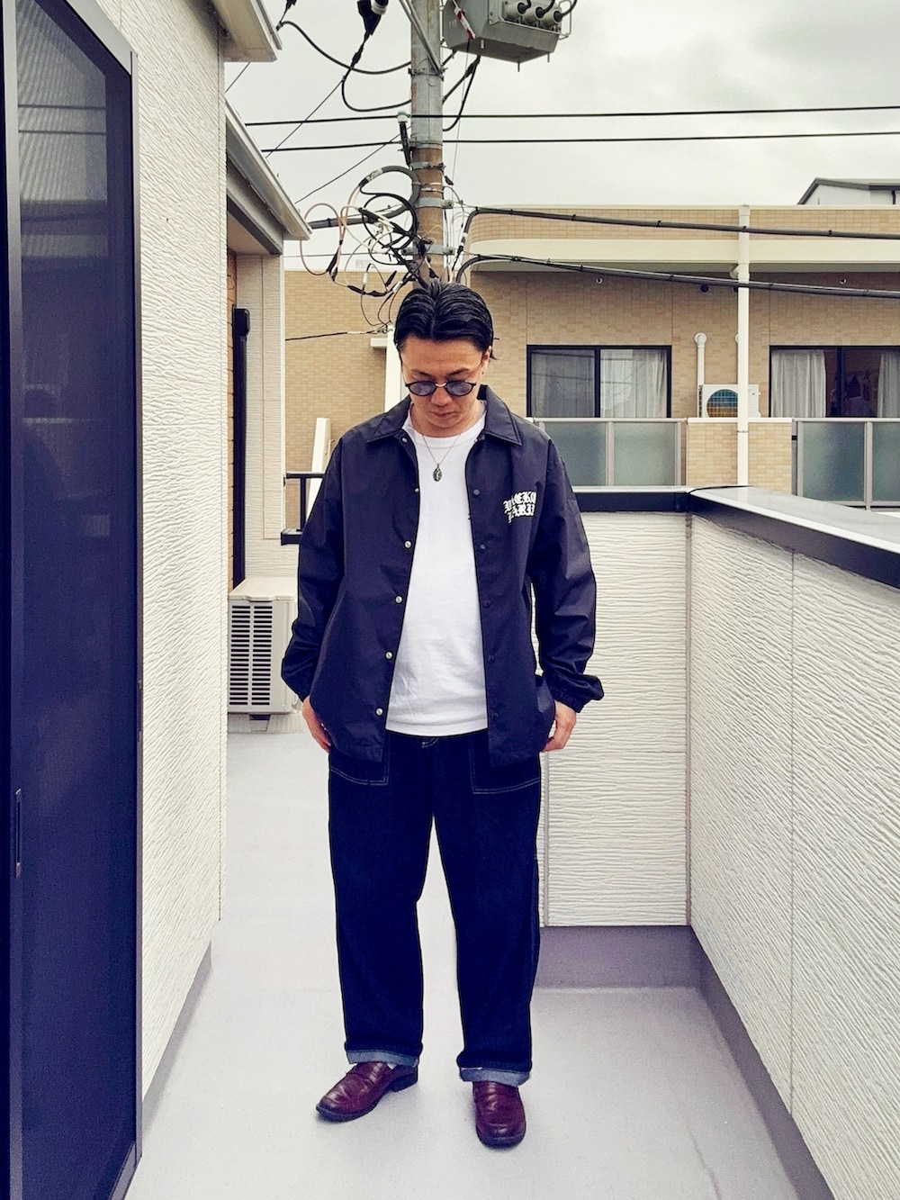 ブルー系のデニムパンツ、ホワイト系のTシャツ/カットソー、ブラック系のジャケット/アウターを着用したメンズの春コーディネートの2枚目の写真