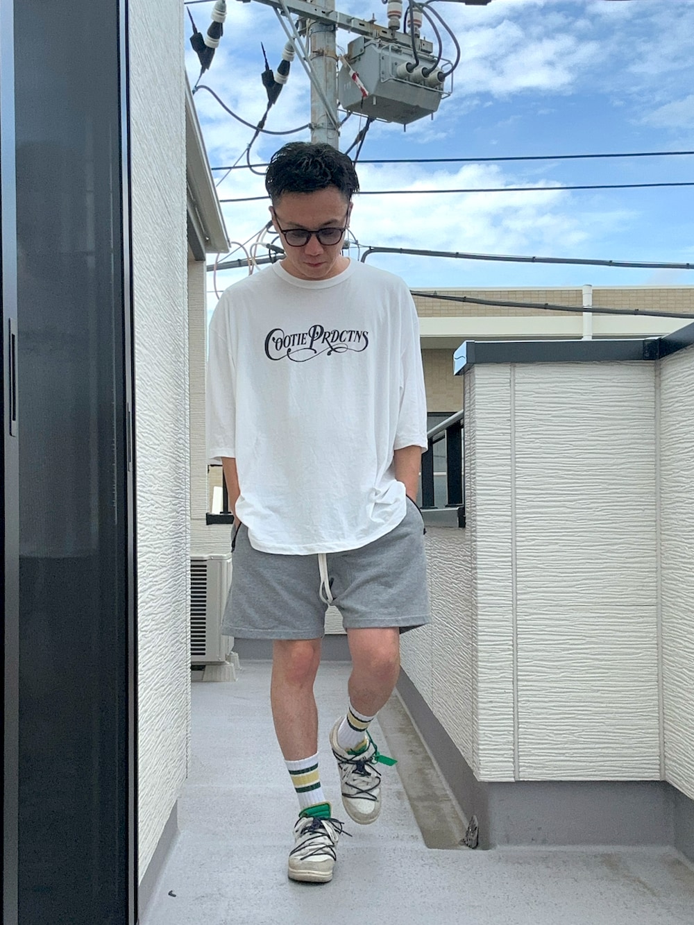 ホワイト系のTシャツ/カットソー、グレー系のパンツ、ホワイト系のスニーカーを着用したメンズの夏コーディネートの2枚目の写真