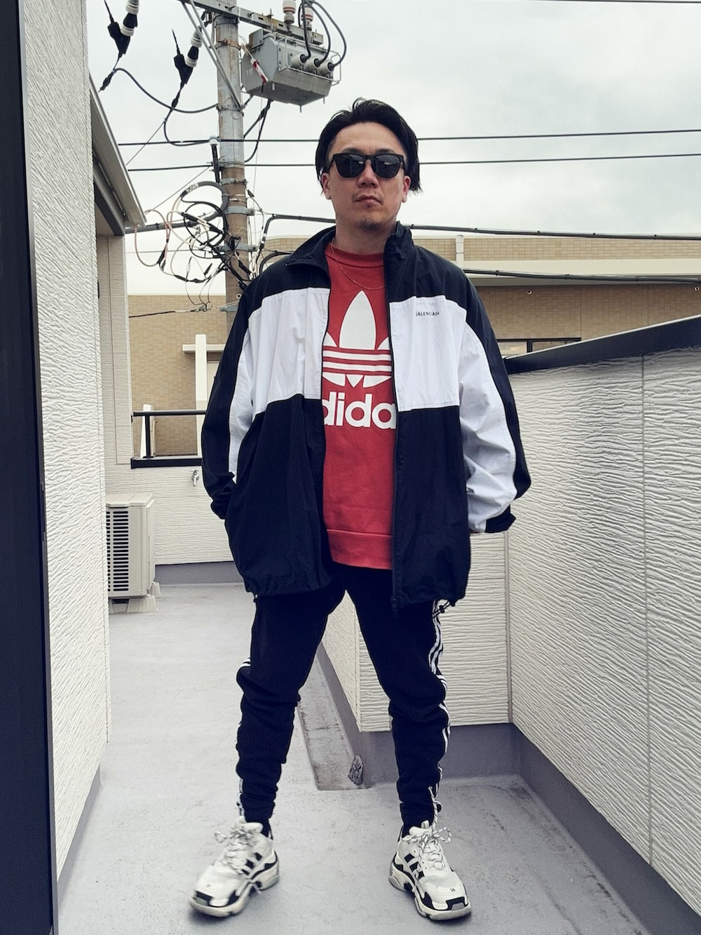 オレンジ系のスウェット、ブラック系のスウェットパンツ、ブラック系のナイロンジャケットを着用したメンズの冬コーディネートの4枚目の写真