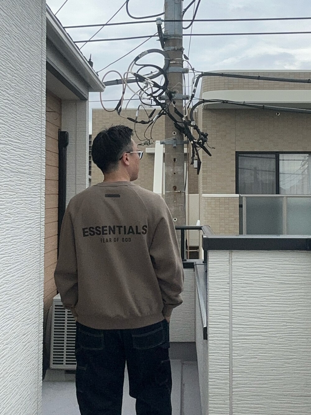 ベージュ系のスウェット、ブルー系のデニムパンツ、ブラック系のシューズを着用したメンズの秋コーディネートの5枚目の写真