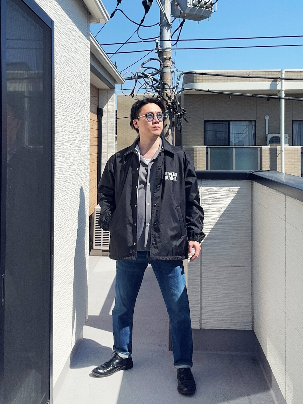 ブルー系のデニムパンツ、グレー系のシャツ/ブラウス、ブラック系のジャケット/アウターを着用したメンズの春コーディネートの2枚目の写真