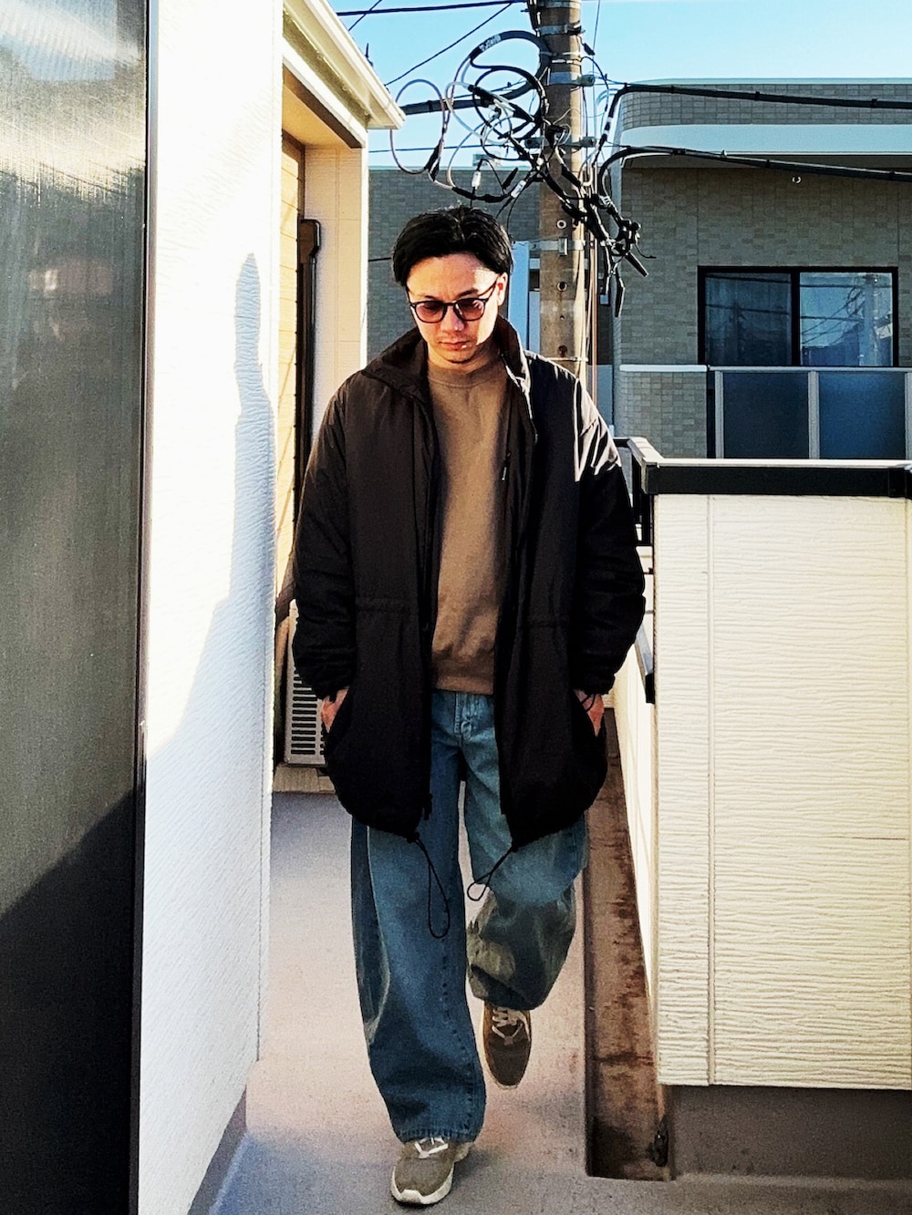 ベージュ系のスウェット、ブラック系のその他アウター、ブルー系のデニムパンツを着用したメンズの冬コーディネートの2枚目の写真