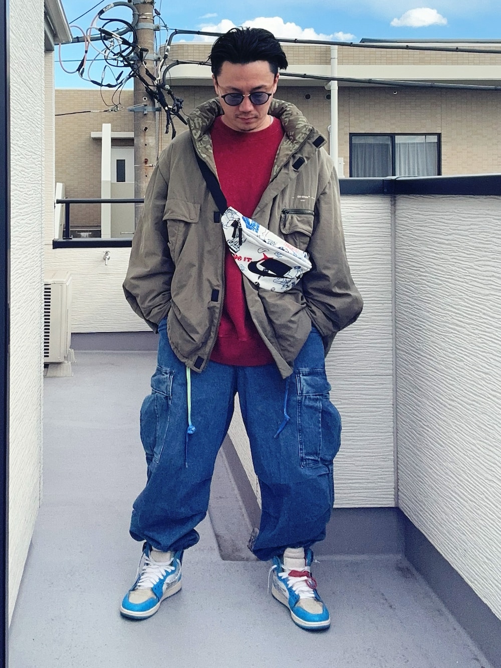 レッド系のスウェット、グリーン系のミリタリージャケット、ブルー系のカーゴパンツを着用したメンズの冬コーディネートの3枚目の写真