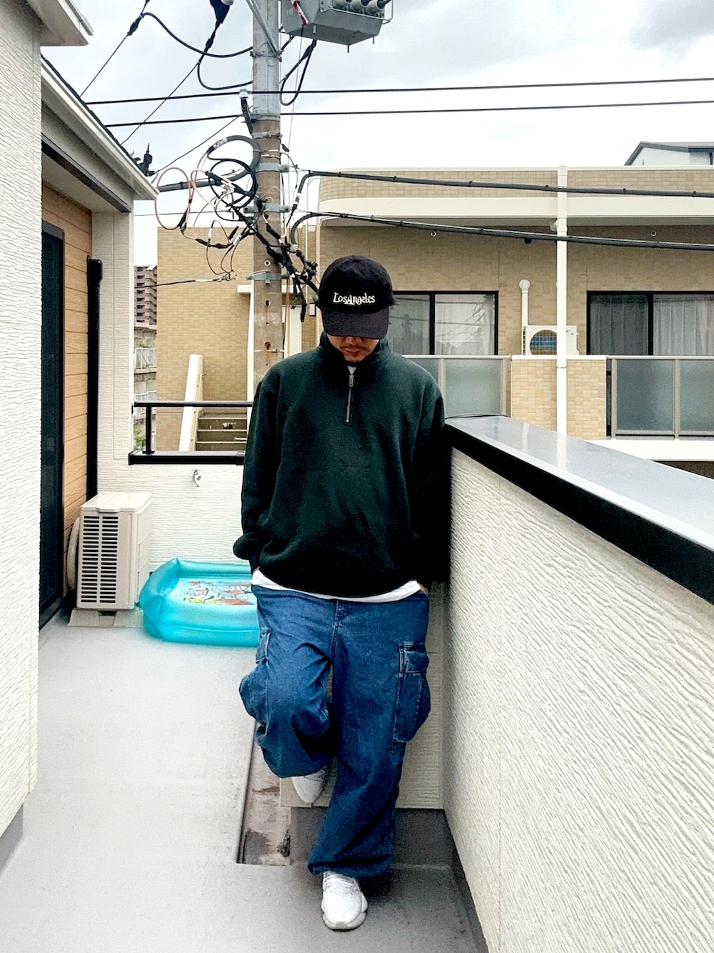 グリーン系のスウェット、ブルー系のカーゴパンツ、ホワイト系のスニーカーを着用したメンズの秋コーディネートの2枚目の写真