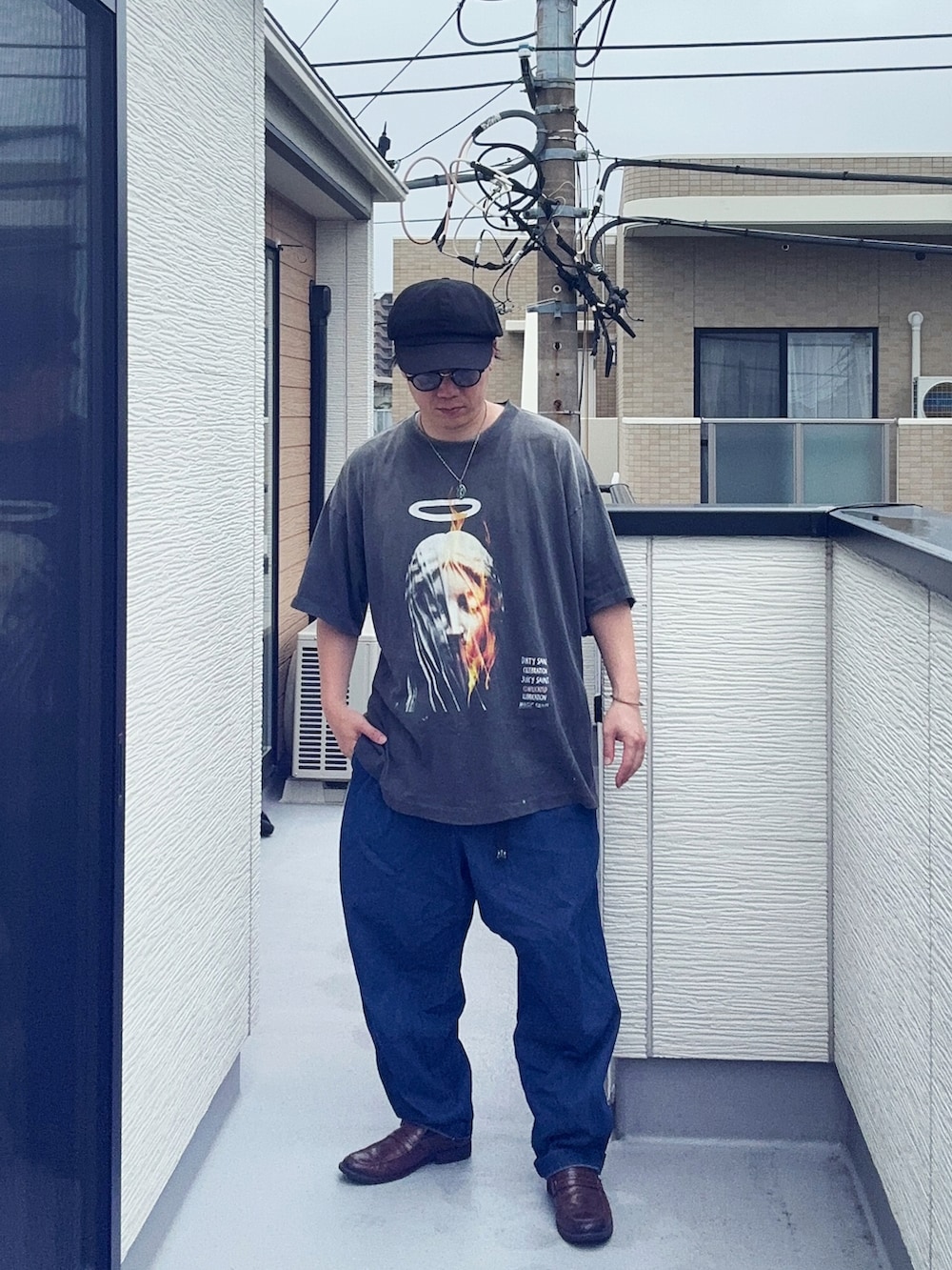 ブルー系のデニムパンツ、ブラック系のTシャツ/カットソー、ブラウン系のローファーを着用したメンズの夏コーディネートの4枚目の写真