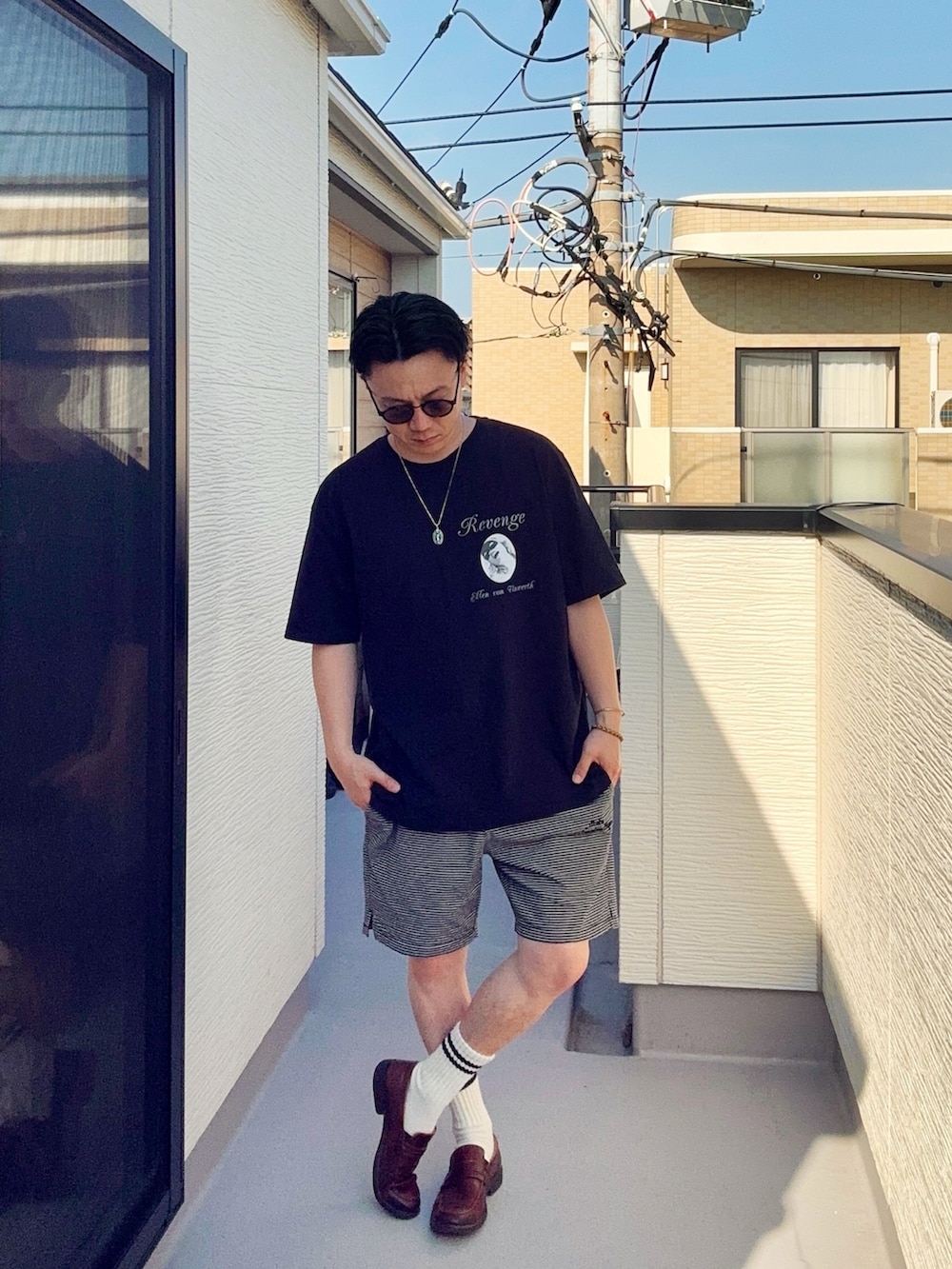 ブラック系のTシャツ/カットソー、ブラック系のパンツ、ブラウン系のローファーを着用したメンズの春コーディネートの2枚目の写真