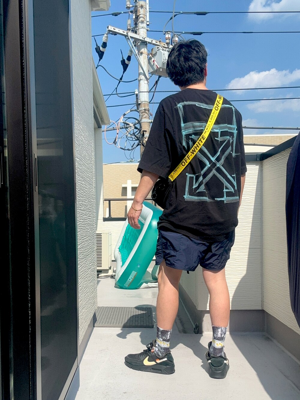 ブラック系のショルダーバッグ、ブラック系のTシャツ/カットソー、ブルー系のパンツを着用したメンズの夏コーディネートの2枚目の写真