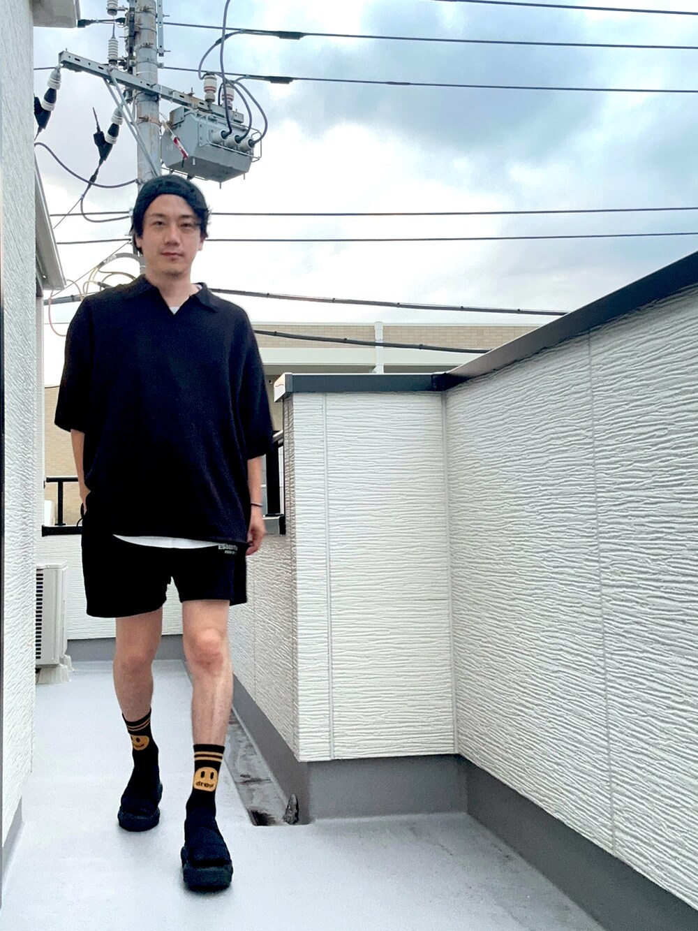 ブラック系のポロシャツ、ブラック系のスウェットパンツ、ブラック系のサンダルを着用したメンズの夏コーディネートの3枚目の写真