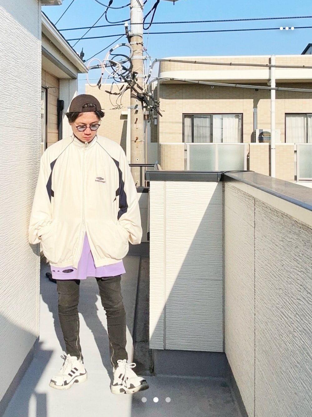 パープル系のTシャツ/カットソー、ホワイト系のナイロンジャケット、ブラック系のデニムパンツを着用したメンズの秋コーディネートの2枚目の写真