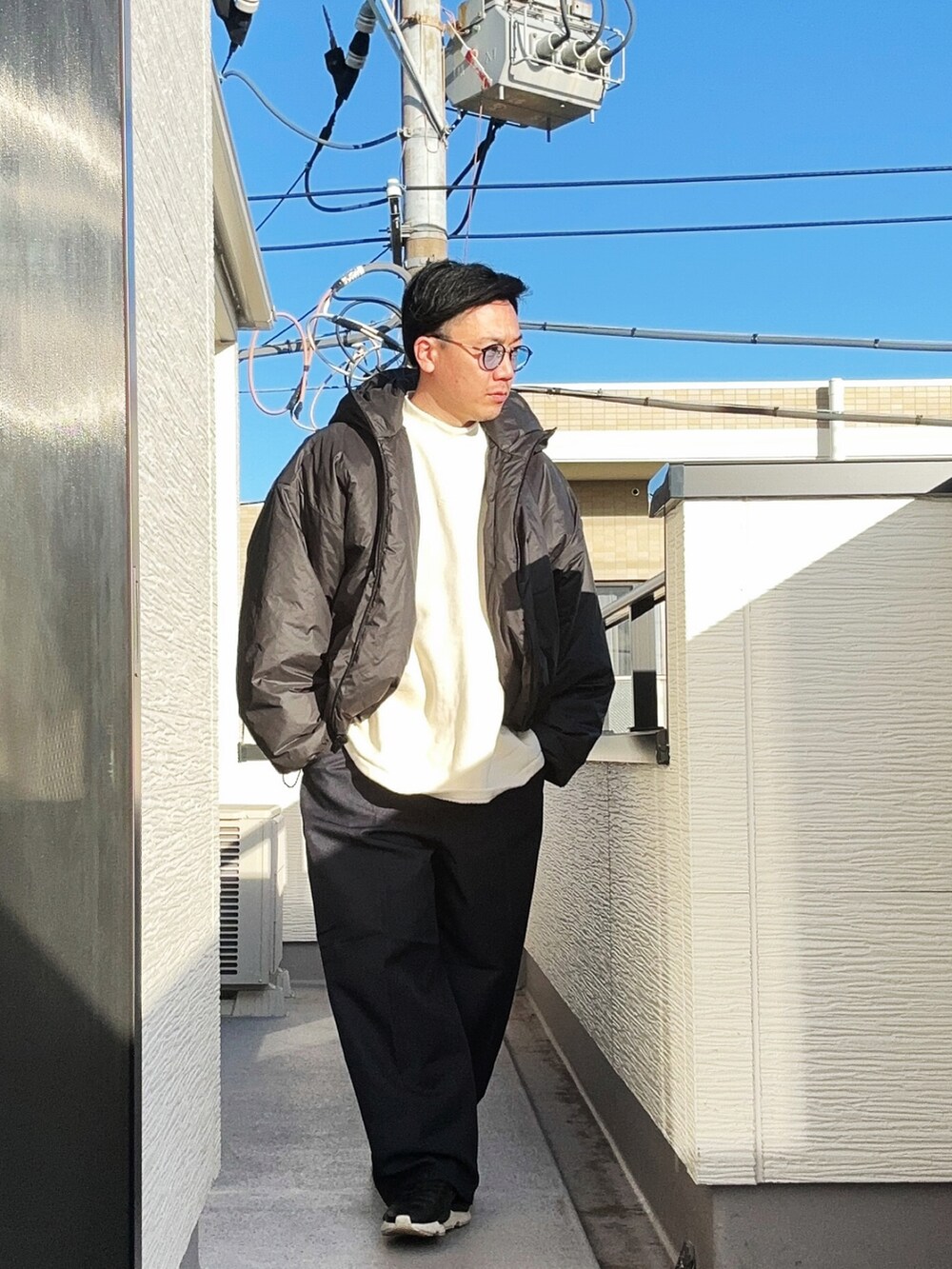 ベージュ系のTシャツ/カットソー、ブラック系のジャケット/アウター、ブルー系のスラックスを着用したメンズの冬コーディネートの3枚目の写真