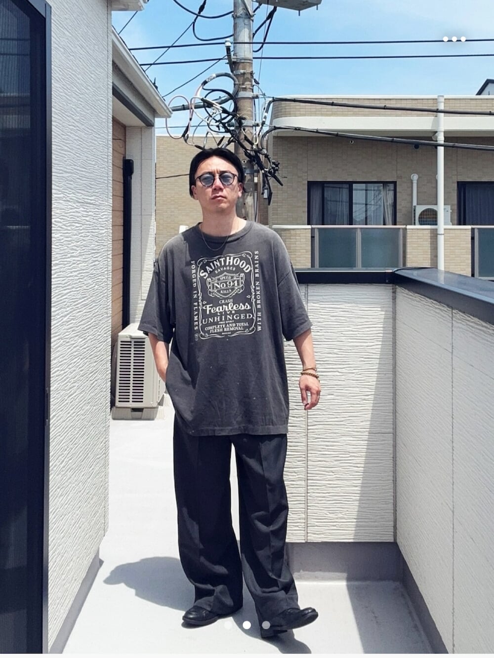 グレー系のスラックス、ブラック系のローファー、ブラック系のTシャツ/カットソーを着用したメンズの夏コーディネートの3枚目の写真