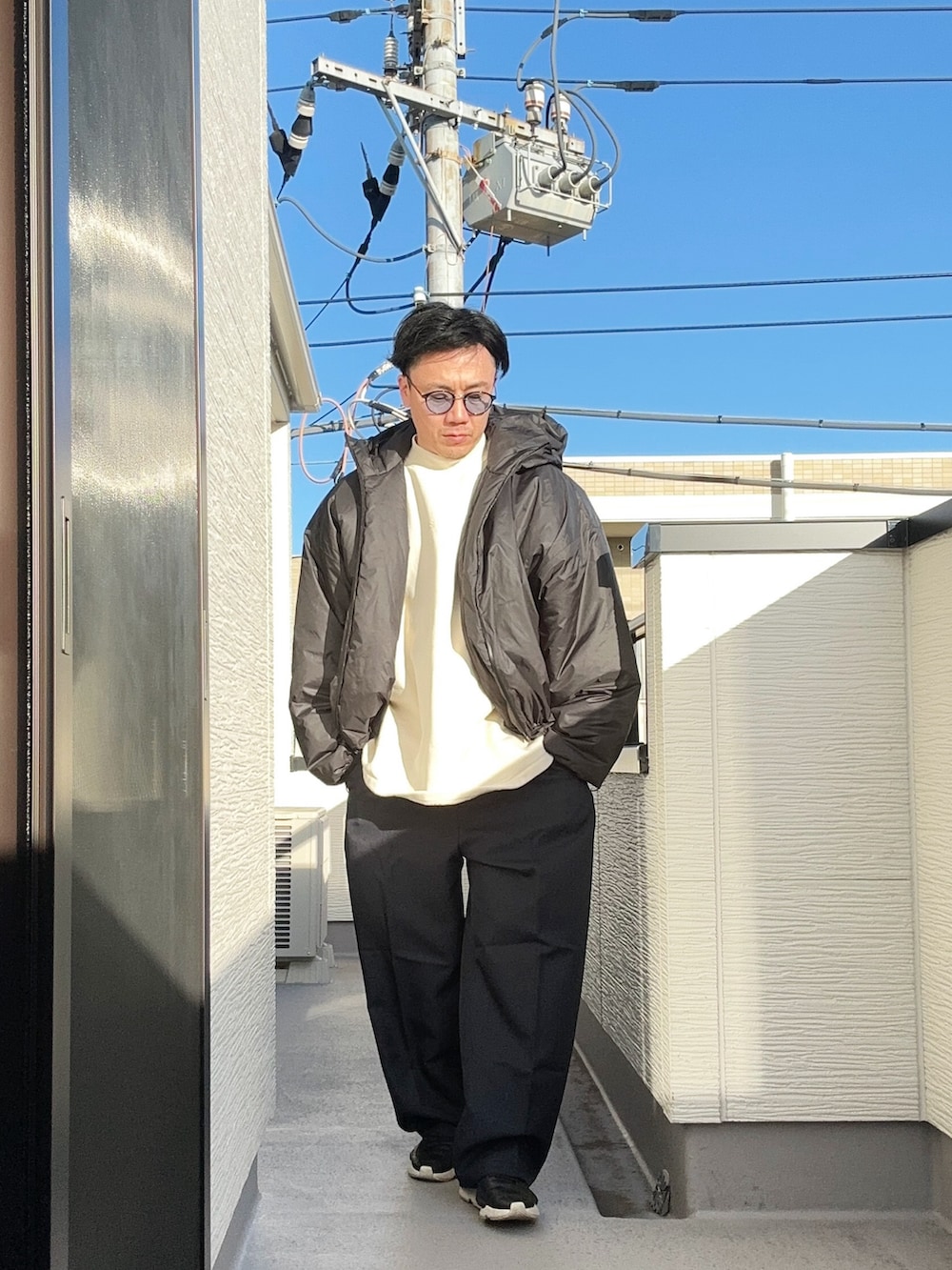 ベージュ系のTシャツ/カットソー、ブラック系のジャケット/アウター、ブルー系のスラックスを着用したメンズの冬コーディネートの2枚目の写真