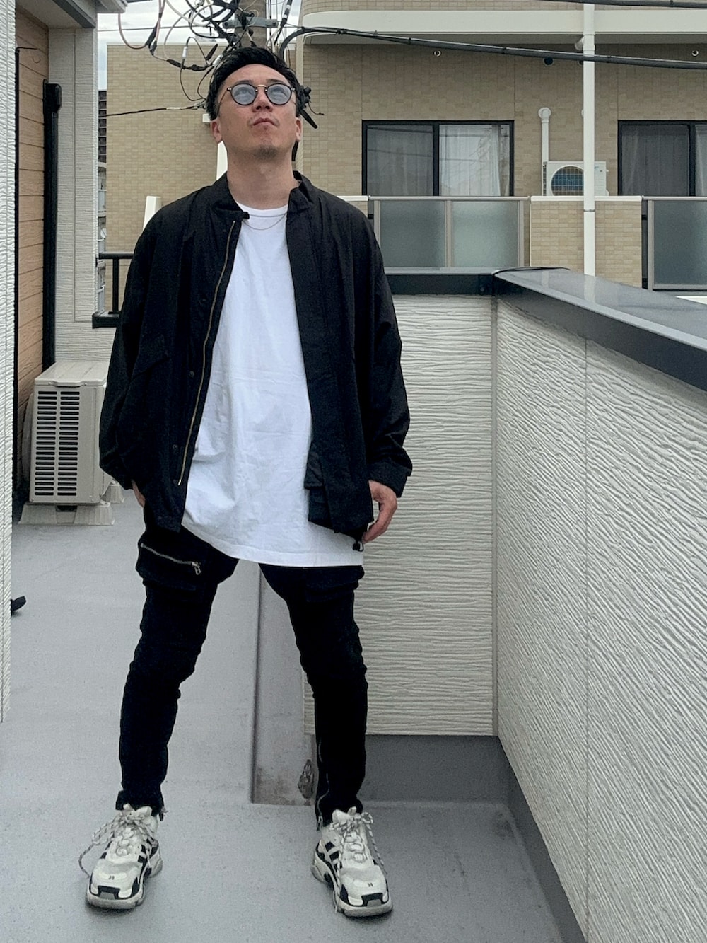 ブラック系のブルゾン、ホワイト系のトップス、ブラック系のデニムパンツを着用したメンズの秋コーディネートの2枚目の写真