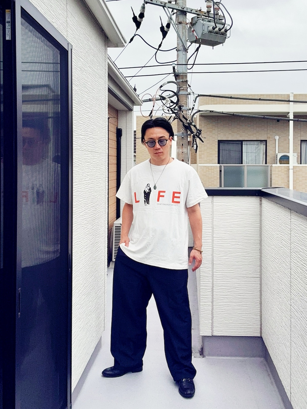 グレー系のスラックス、ブラック系のローファー、ホワイト系のTシャツ/カットソーを着用したメンズの夏コーディネートの3枚目の写真