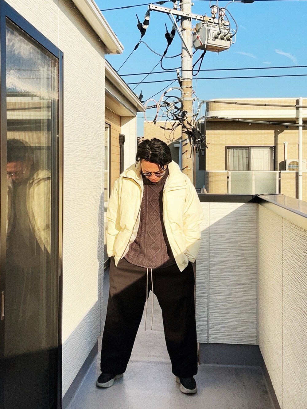 ブラック系のニット/セーター、ベージュ系のダウンジャケット/コート、ブラック系のスウェットパンツを着用したメンズの冬コーディネートの2枚目の写真