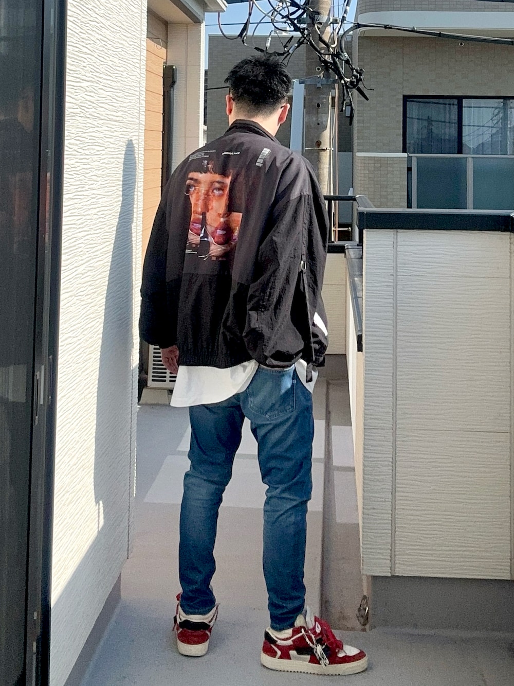 ブルー系のデニムパンツ、ホワイト系のトップス、ブラック系のジャケット/アウターを着用したメンズの秋コーディネートの2枚目の写真