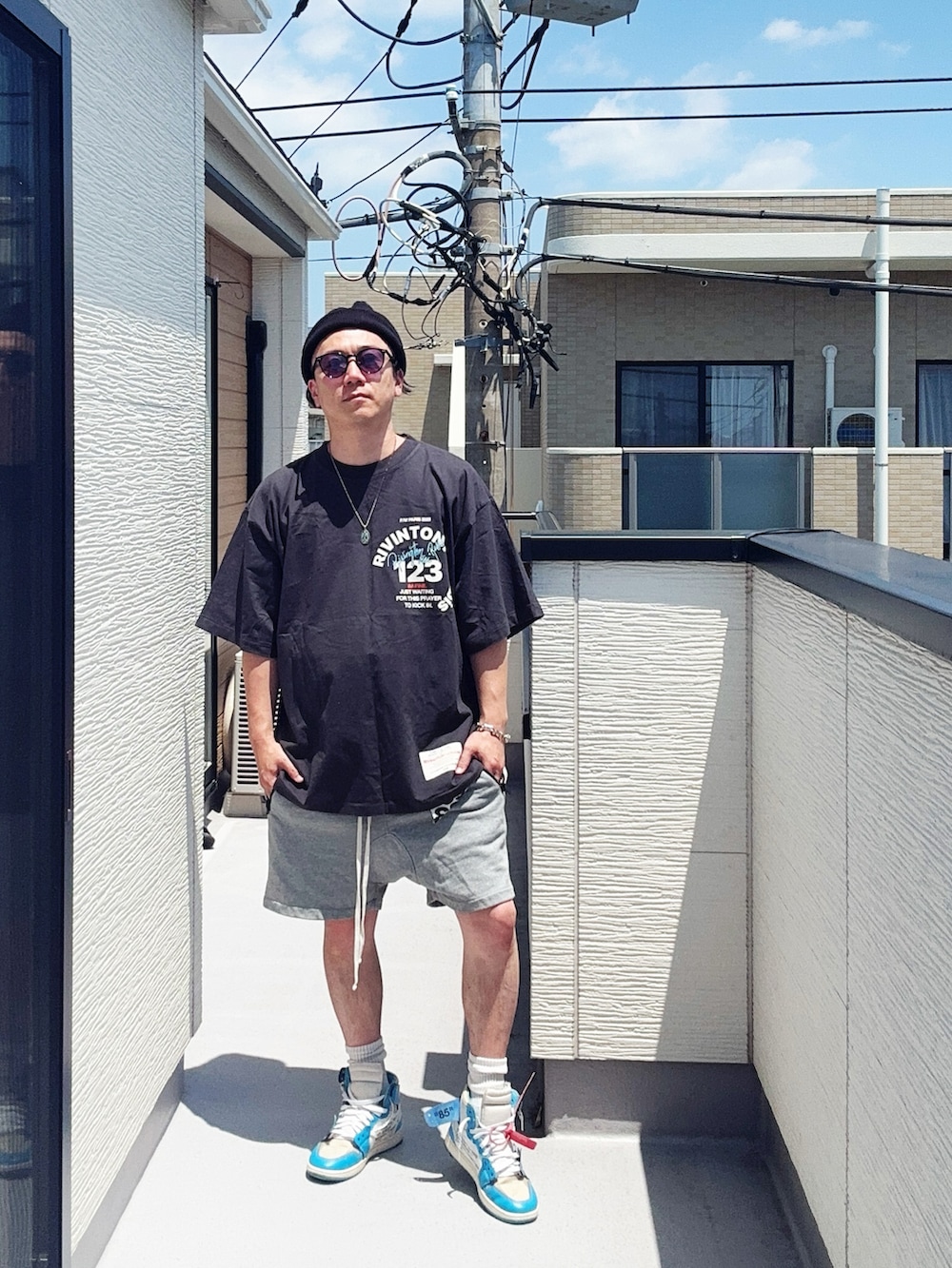 ブラック系のTシャツ/カットソー、グレー系のパンツ、ブルー系のスニーカーを着用したメンズの夏コーディネートの3枚目の写真