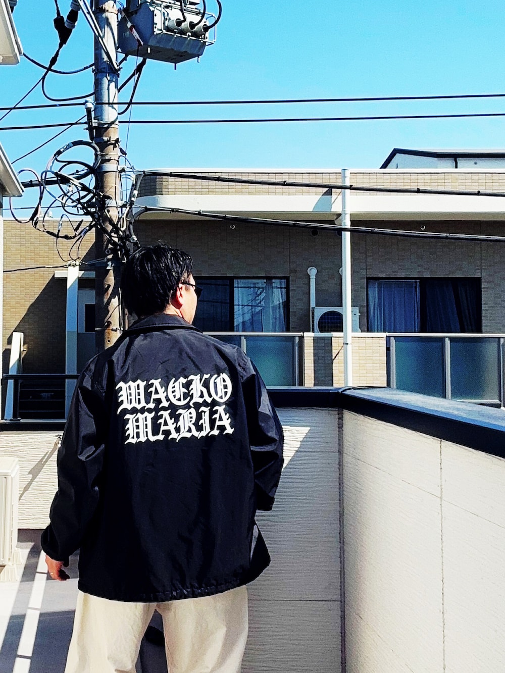 グレー系のシャツ/ブラウス、ブラック系のジャケット/アウター、ホワイト系のチノパンツを着用したメンズの春コーディネートの3枚目の写真