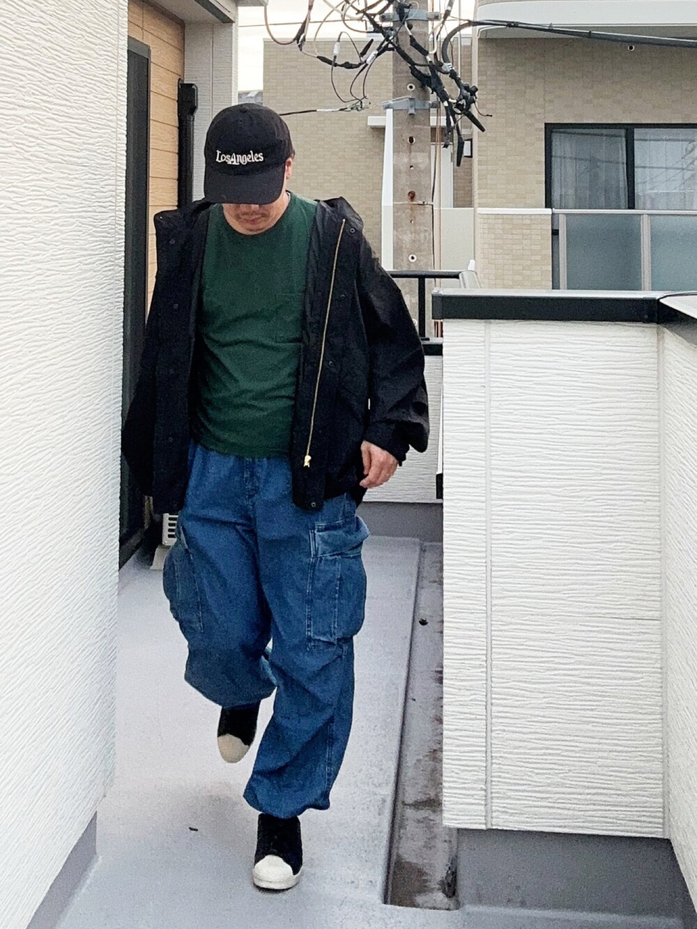 グリーン系のTシャツ/カットソー、ブラック系のブルゾン、ブルー系のカーゴパンツを着用したメンズの秋コーディネートの2枚目の写真