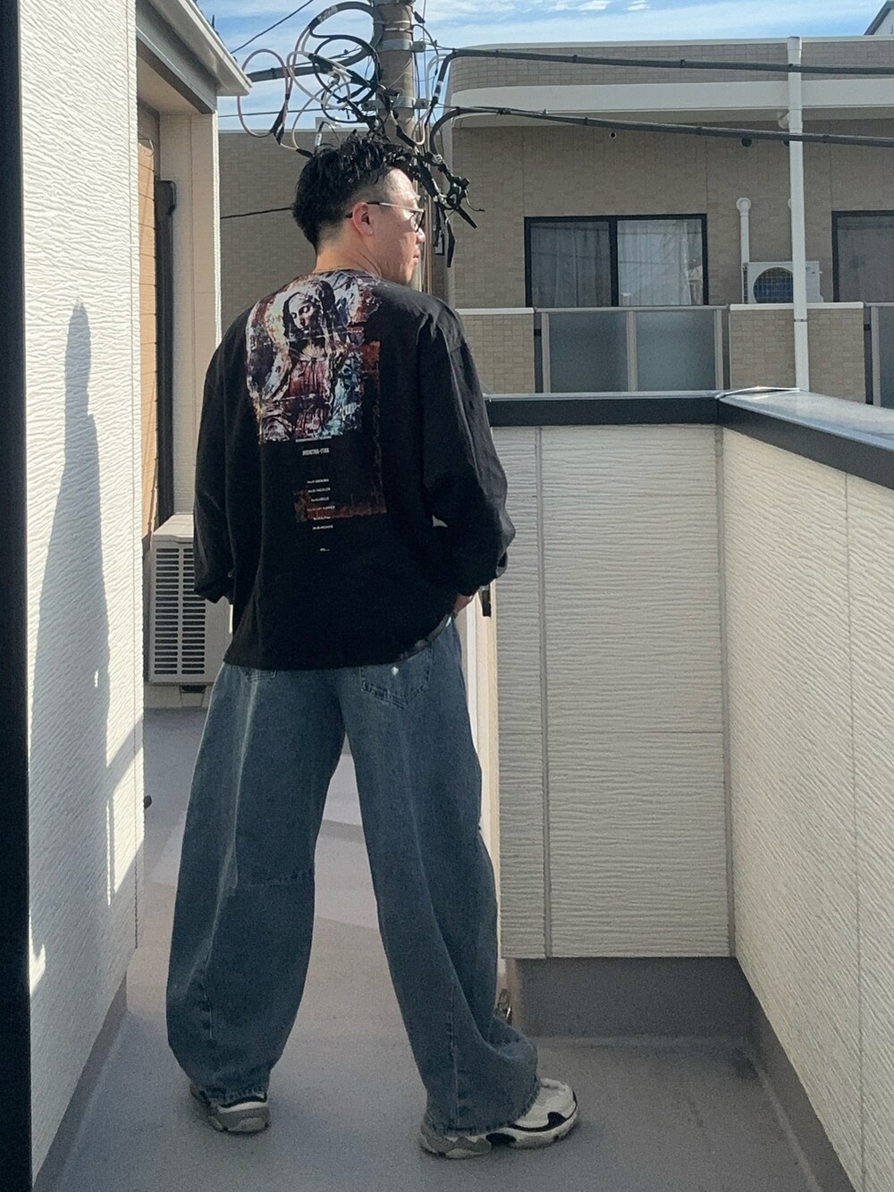 ブルー系のデニムパンツ、ブラック系のTシャツ/カットソー、ホワイト系のシューズを着用したメンズの秋コーディネートの4枚目の写真