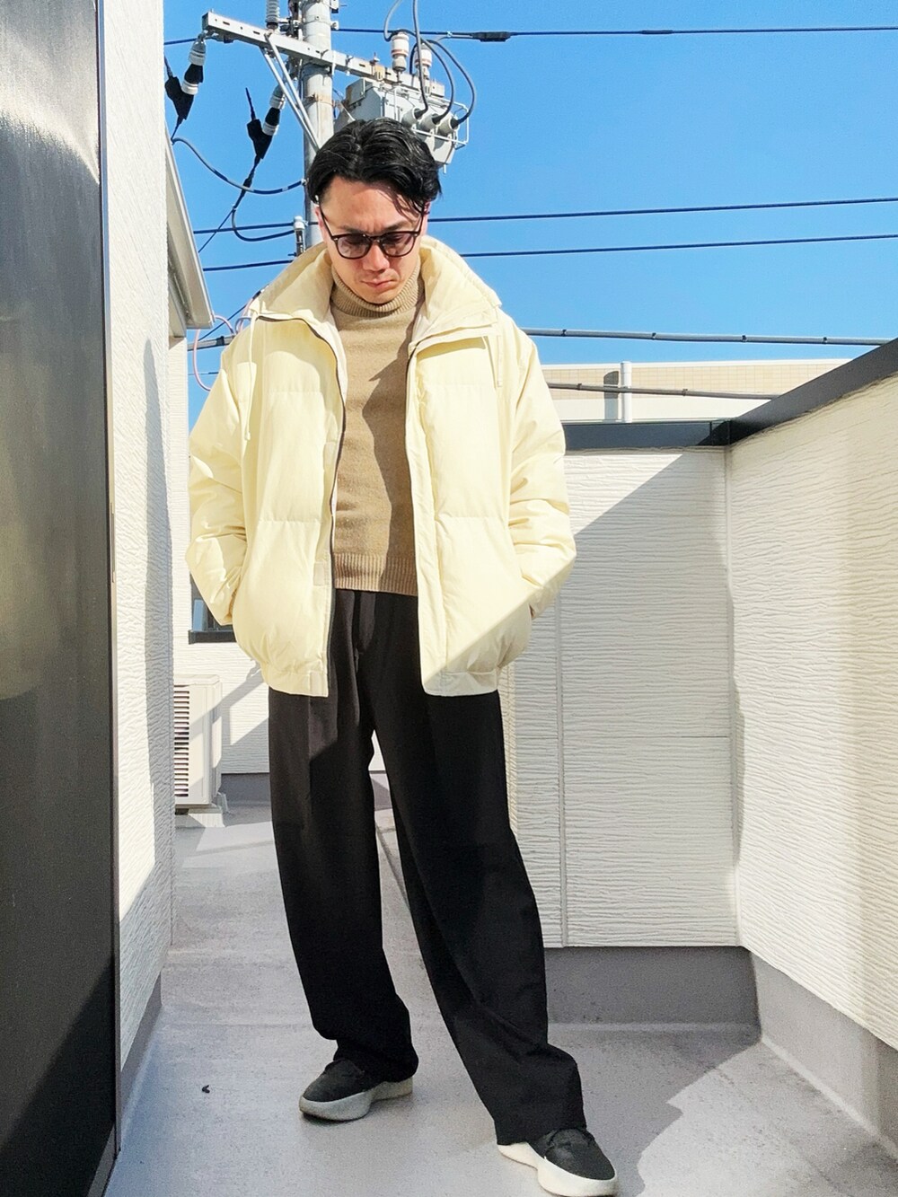 ベージュ系のニット/セーター、ベージュ系のダウンジャケット/コート、ブラック系のスラックスを着用したメンズの冬コーディネートの4枚目の写真