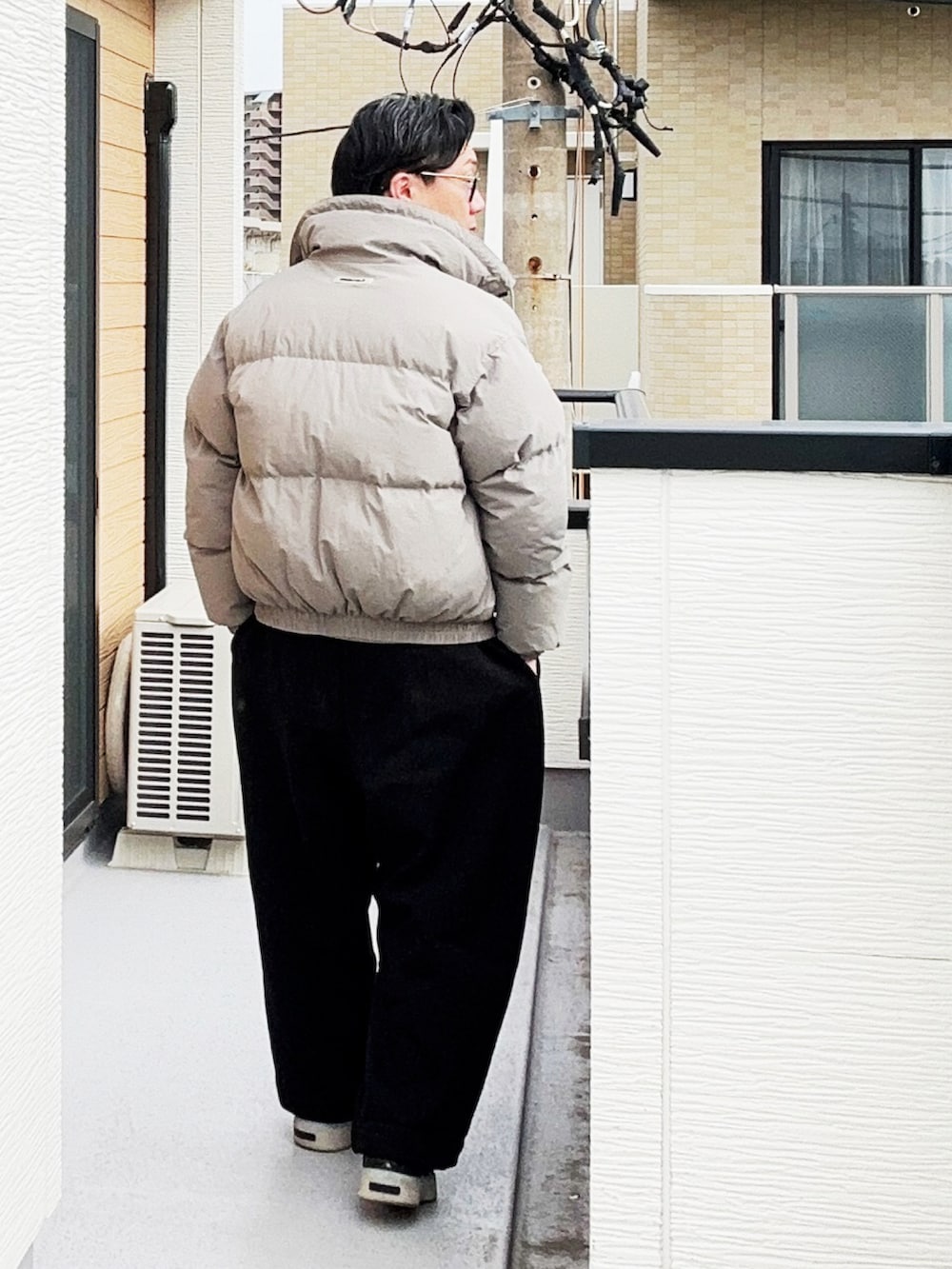 グレー系のポロシャツ、グレー系のダウンジャケット/コート、ブラック系のスウェットパンツを着用したメンズの冬コーディネートの4枚目の写真