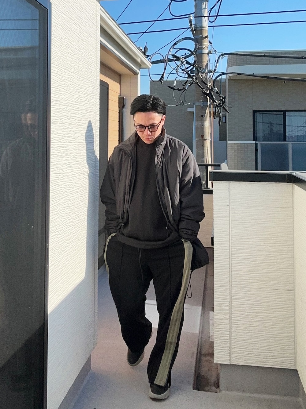 ブラック系のその他アウター、ブラック系のスウェット、ブラック系のパンツを着用したメンズの冬コーディネートの2枚目の写真