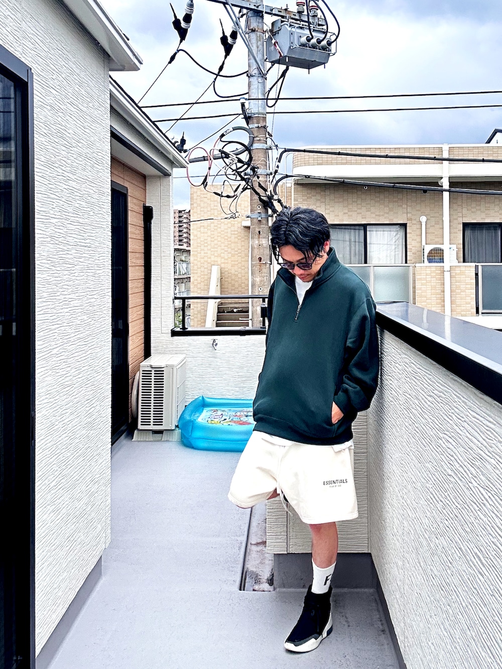 グリーン系のスウェット、ホワイト系のスウェットパンツ、ブラック系のスニーカーを着用したメンズの秋コーディネートの3枚目の写真