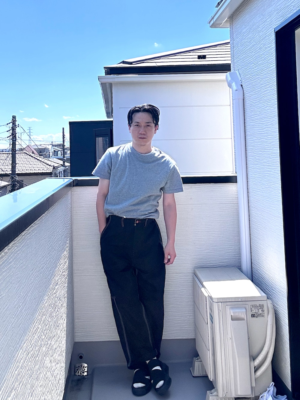 グレー系のTシャツ/カットソー、ブラック系のデニムパンツ、ブラック系のサンダルを着用したメンズの夏コーディネートの4枚目の写真