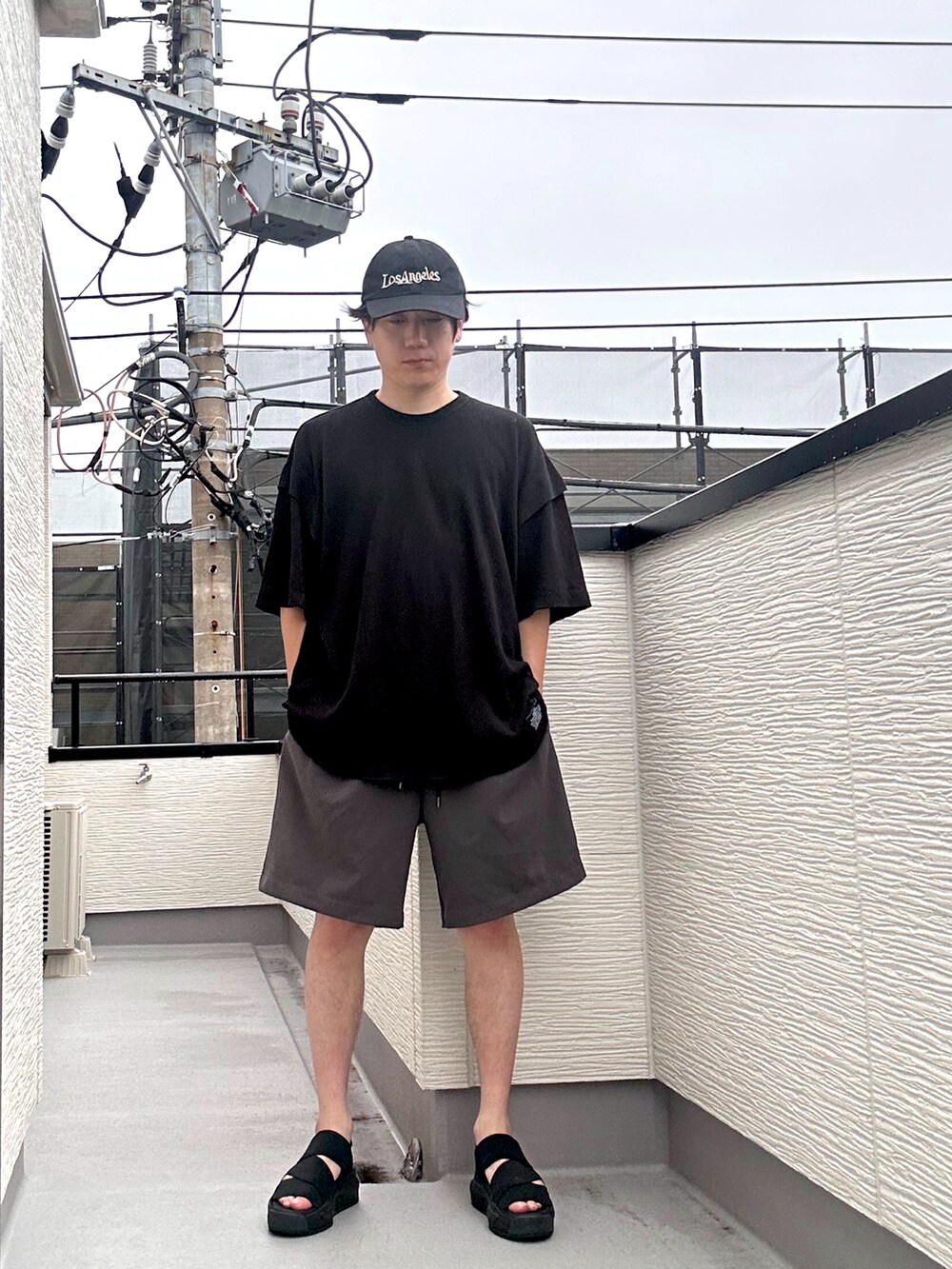 ブラック系のTシャツ/カットソー、グレー系のその他パンツ、ブラック系のサンダルを着用したメンズの夏コーディネートの3枚目の写真