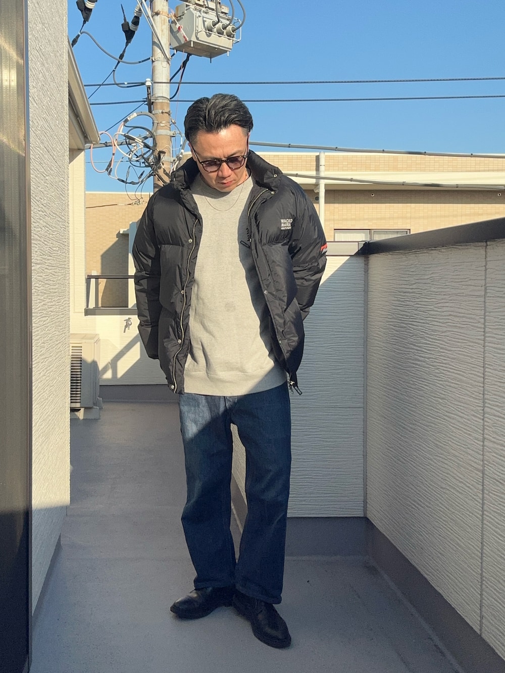 ブラック系のその他アウター、グレー系のスウェット、ブルー系のデニムパンツを着用したメンズの冬コーディネートの4枚目の写真