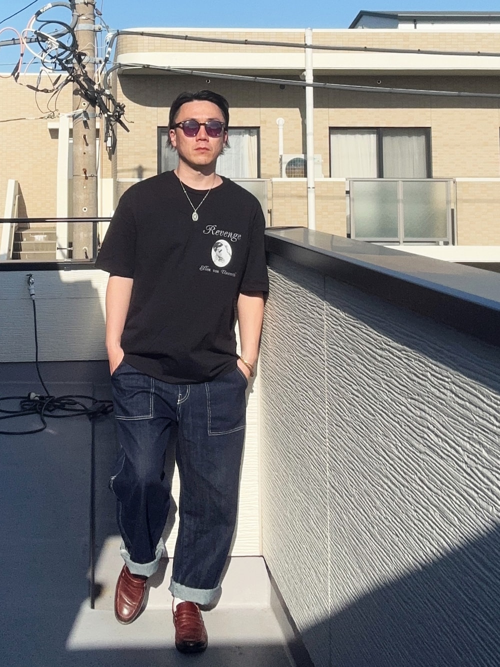 ブルー系のデニムパンツ、ブラック系のTシャツ/カットソー、ブラウン系のローファーを着用したメンズの春コーディネートの2枚目の写真