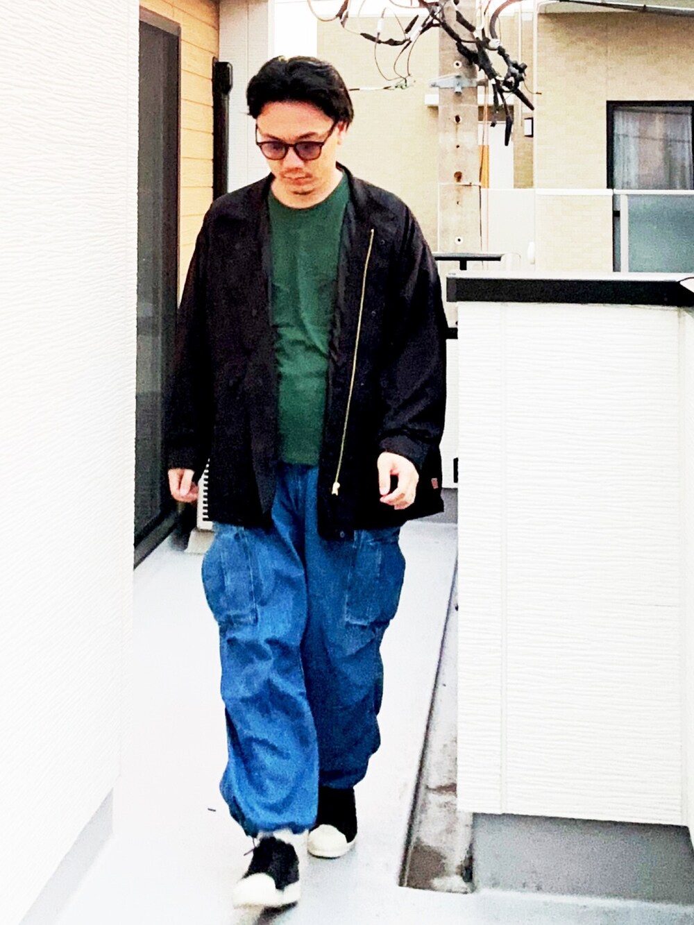 グリーン系のTシャツ/カットソー、ブラック系のブルゾン、ブルー系のカーゴパンツを着用したメンズの秋コーディネートの4枚目の写真