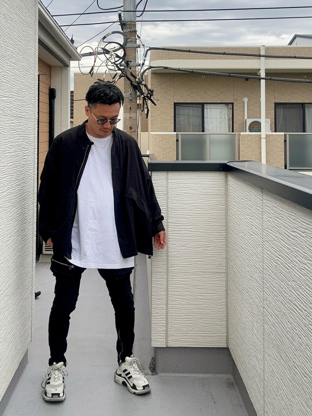 ブラック系のブルゾン、ホワイト系のトップス、ブラック系のデニムパンツを着用したメンズの秋コーディネートの4枚目の写真