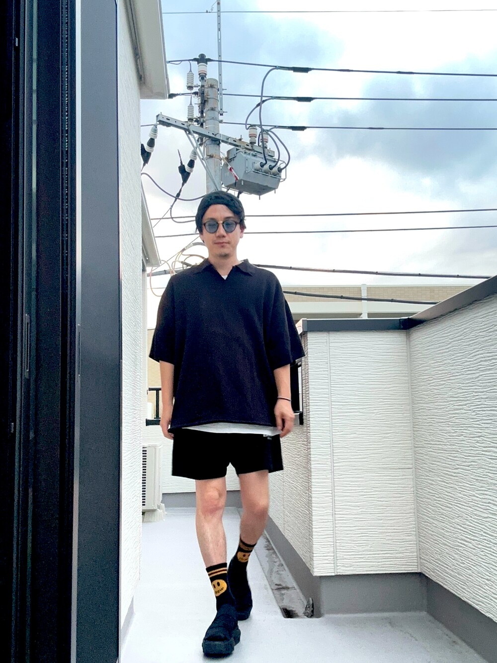 ブラック系のポロシャツ、ブラック系のスウェットパンツ、ブラック系のサンダルを着用したメンズの夏コーディネートの2枚目の写真