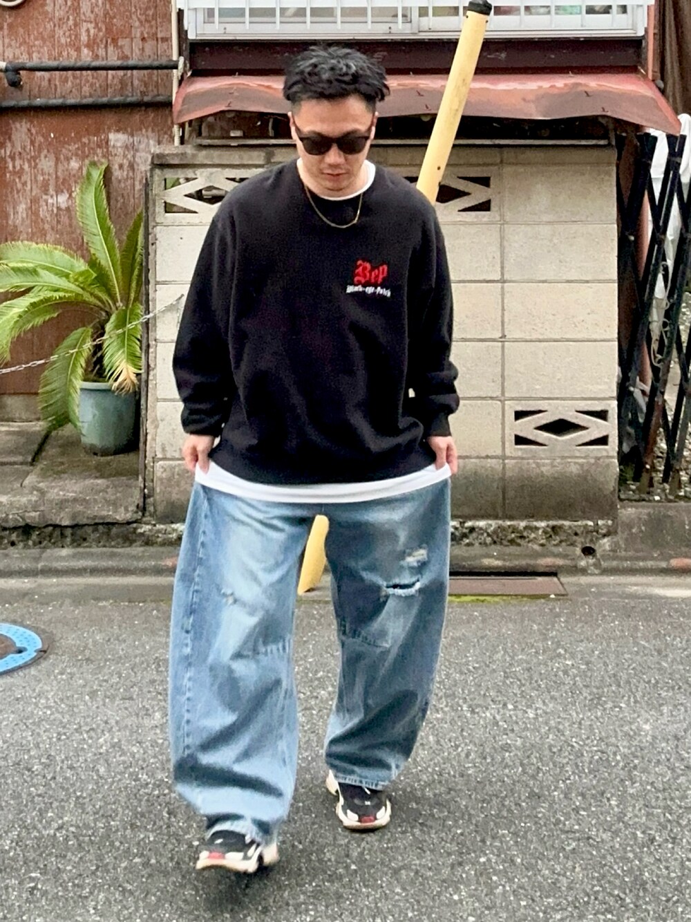 ブルー系のデニムパンツ、ブラック系のスウェット、ブラック系のスニーカーを着用したメンズの秋コーディネートの3枚目の写真