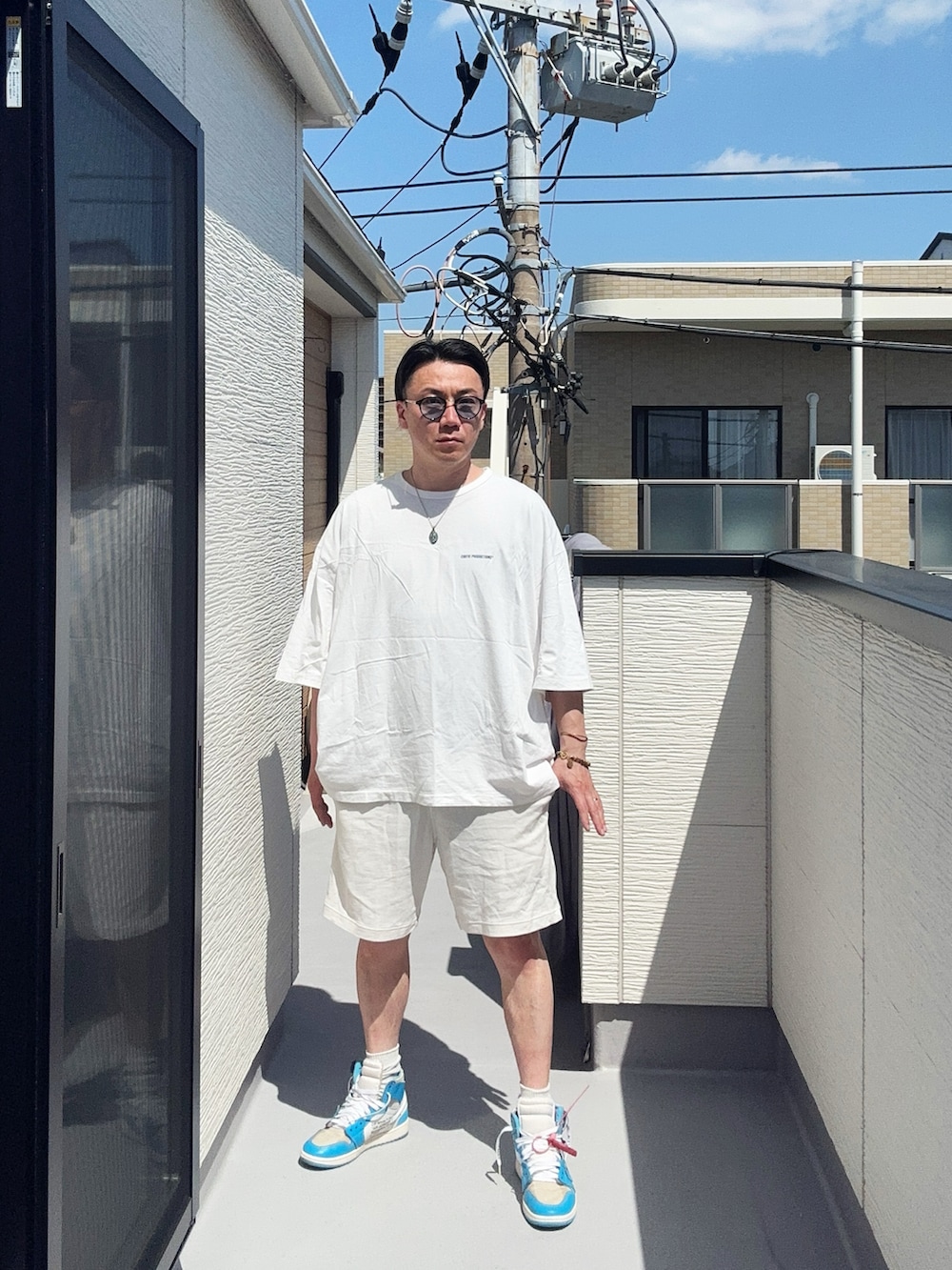 ホワイト系のTシャツ/カットソー、ホワイト系のパンツ、ブルー系のスニーカーを着用したメンズの春コーディネートの2枚目の写真