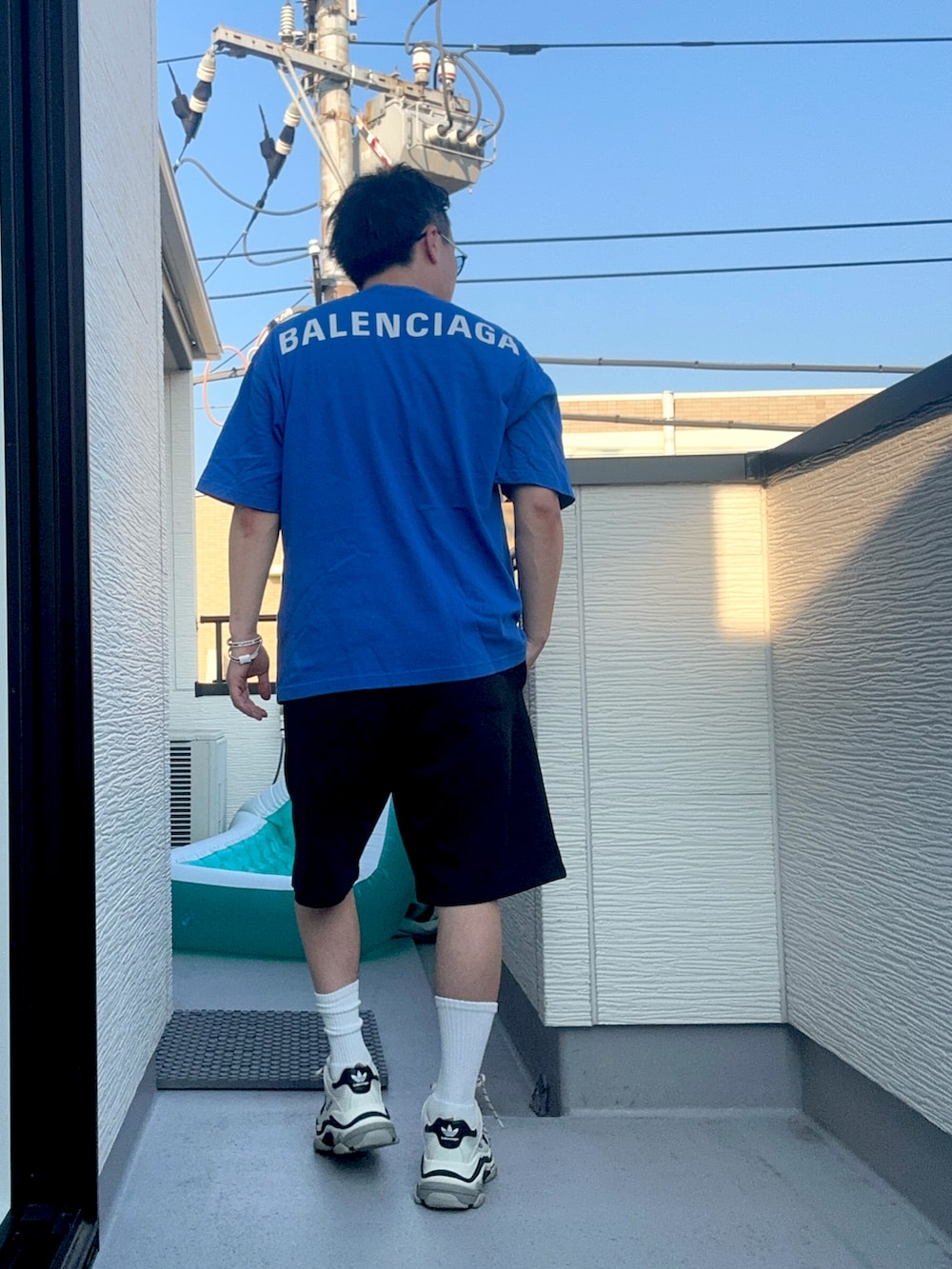 ブルー系のTシャツ/カットソー、ブラック系のスウェットパンツ、ホワイト系のシューズを着用したメンズの秋コーディネートの3枚目の写真