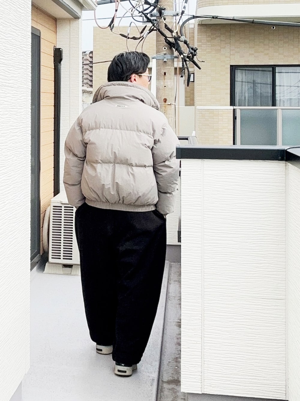 グレー系のポロシャツ、グレー系のダウンジャケット/コート、ブラック系のスウェットパンツを着用したメンズの冬コーディネートの3枚目の写真