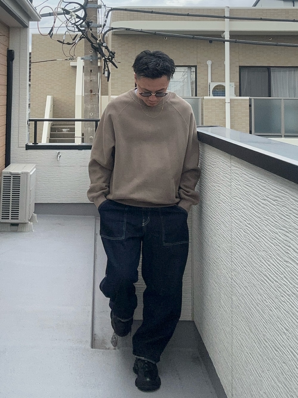 ベージュ系のスウェット、ブルー系のデニムパンツ、ブラック系のシューズを着用したメンズの秋コーディネートの2枚目の写真