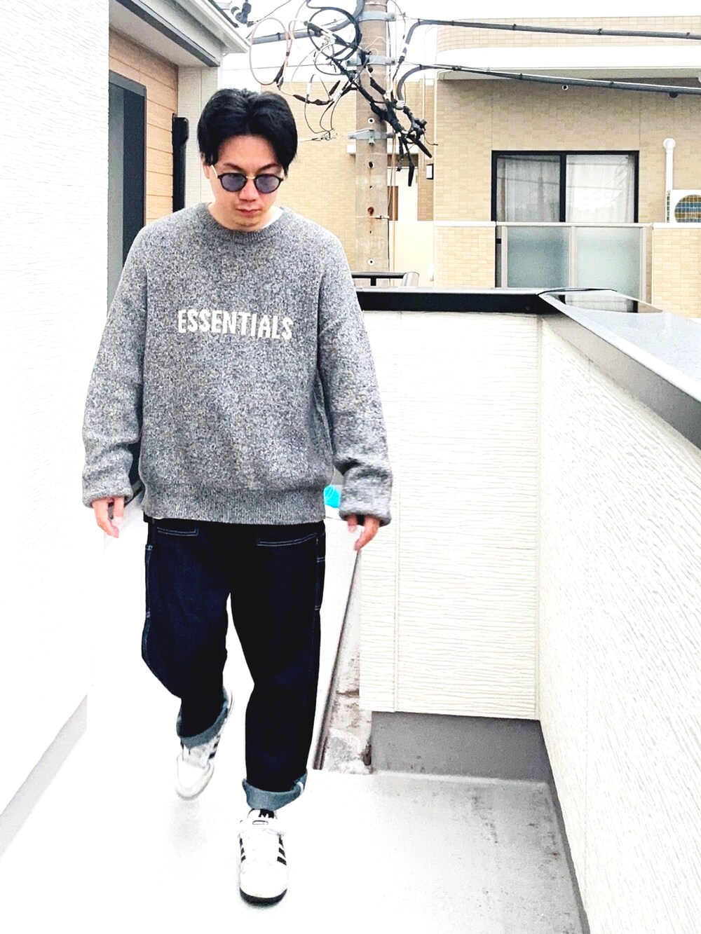 ブルー系のデニムパンツ、ホワイト系のスニーカー、グレー系のニット/セーターを着用したメンズの秋コーディネートの2枚目の写真