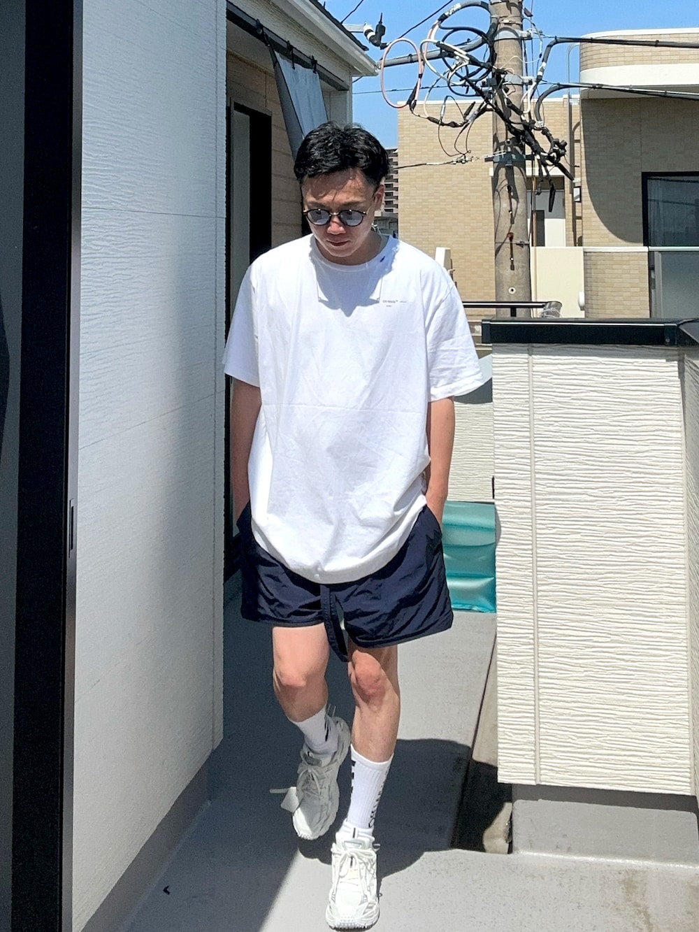 ホワイト系のトップス、ブルー系のパンツ、ホワイト系のスニーカーを着用したメンズの夏コーディネートの3枚目の写真