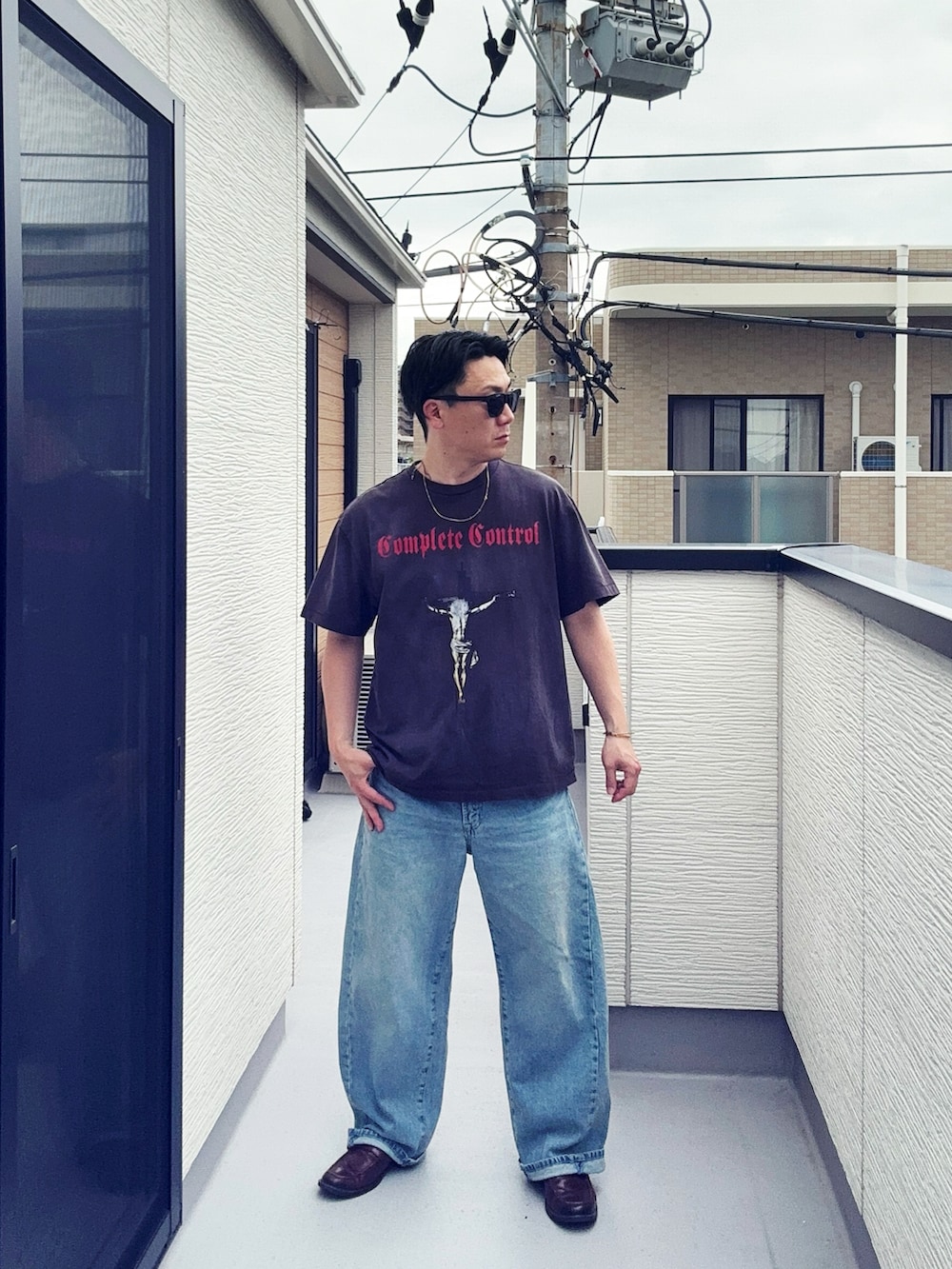 ブラック系のTシャツ/カットソー、ブルー系のデニムパンツ、ブラウン系のローファーを着用したメンズの春コーディネートの3枚目の写真