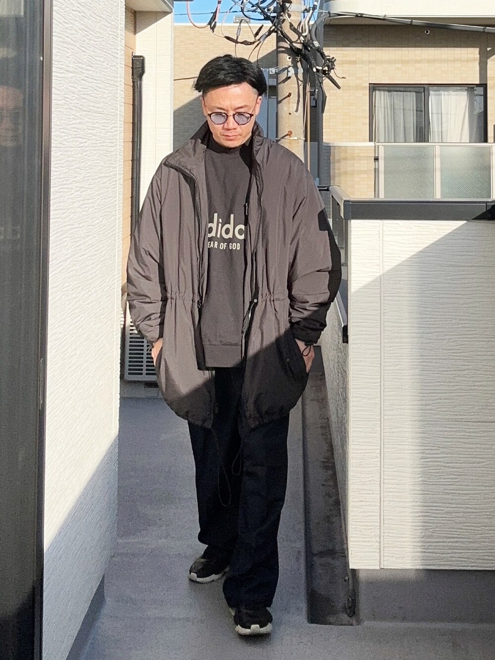 ブラック系のスウェット、ブルー系のスラックス、ブラック系のスニーカーを着用したメンズの冬コーディネートの3枚目の写真