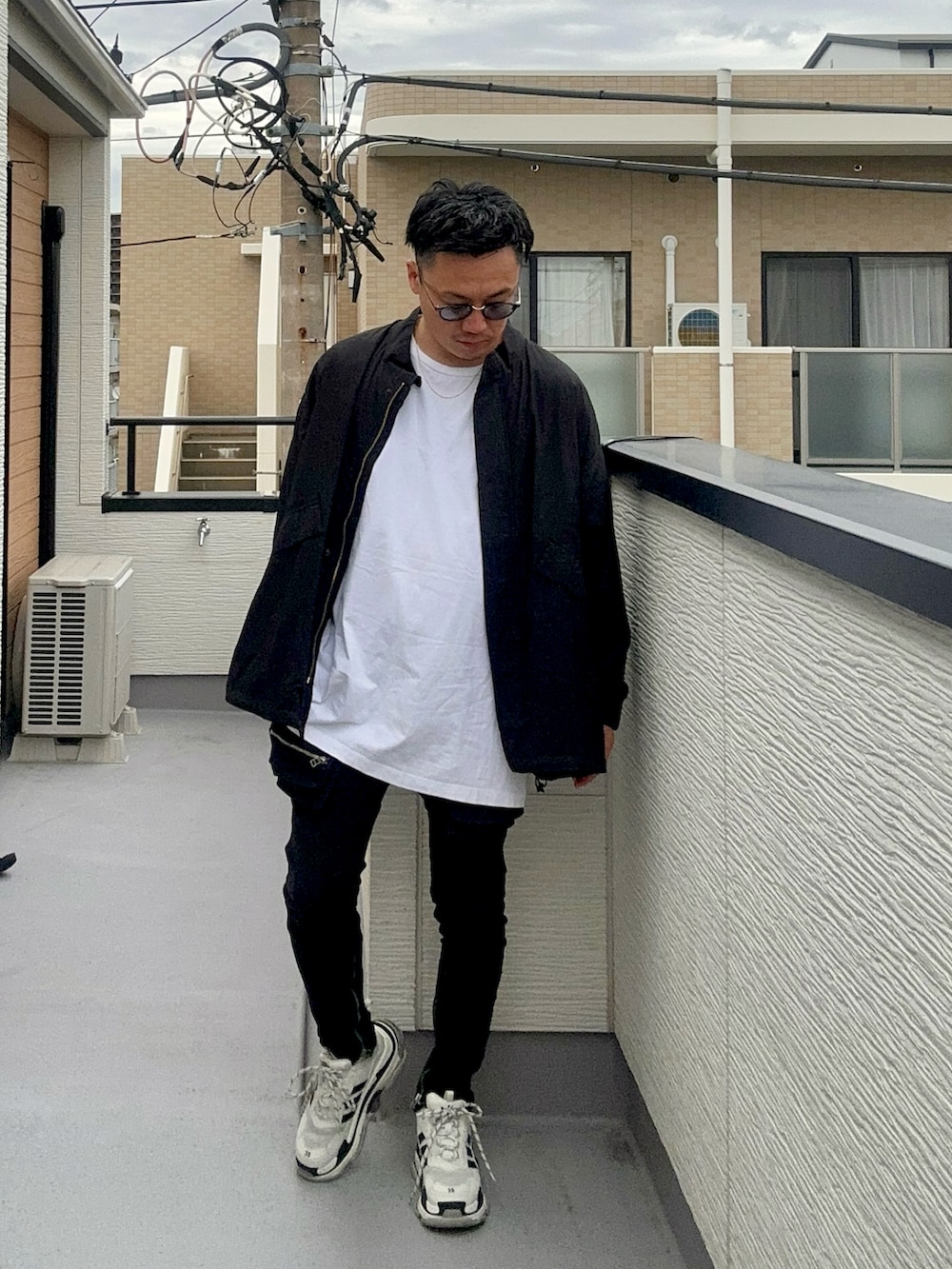 ブラック系のブルゾン、ホワイト系のトップス、ブラック系のデニムパンツを着用したメンズの秋コーディネートの5枚目の写真