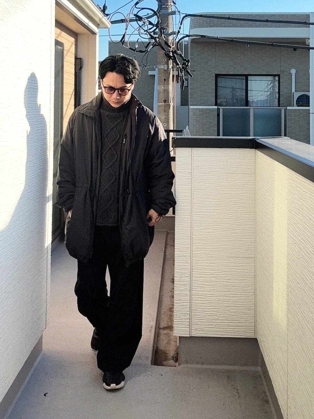 ブラック系のニット/セーター、ブラック系のナイロンジャケット、ブラック系のスラックスを着用したメンズの冬コーディネートの2枚目の写真